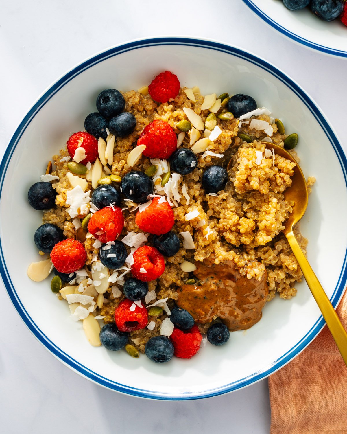 Mediterranean diet breakfast recipes: quinoa in bowl topped with berries, nuts and almond butter.