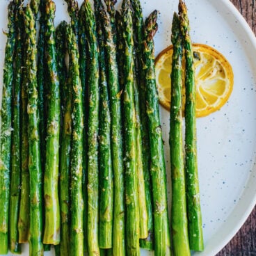 Broiled Asparagus recipe with spears on plate with lemon slice.