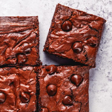 Photo of fudgy olive oil brownies with shiny tops and chocolate chips.