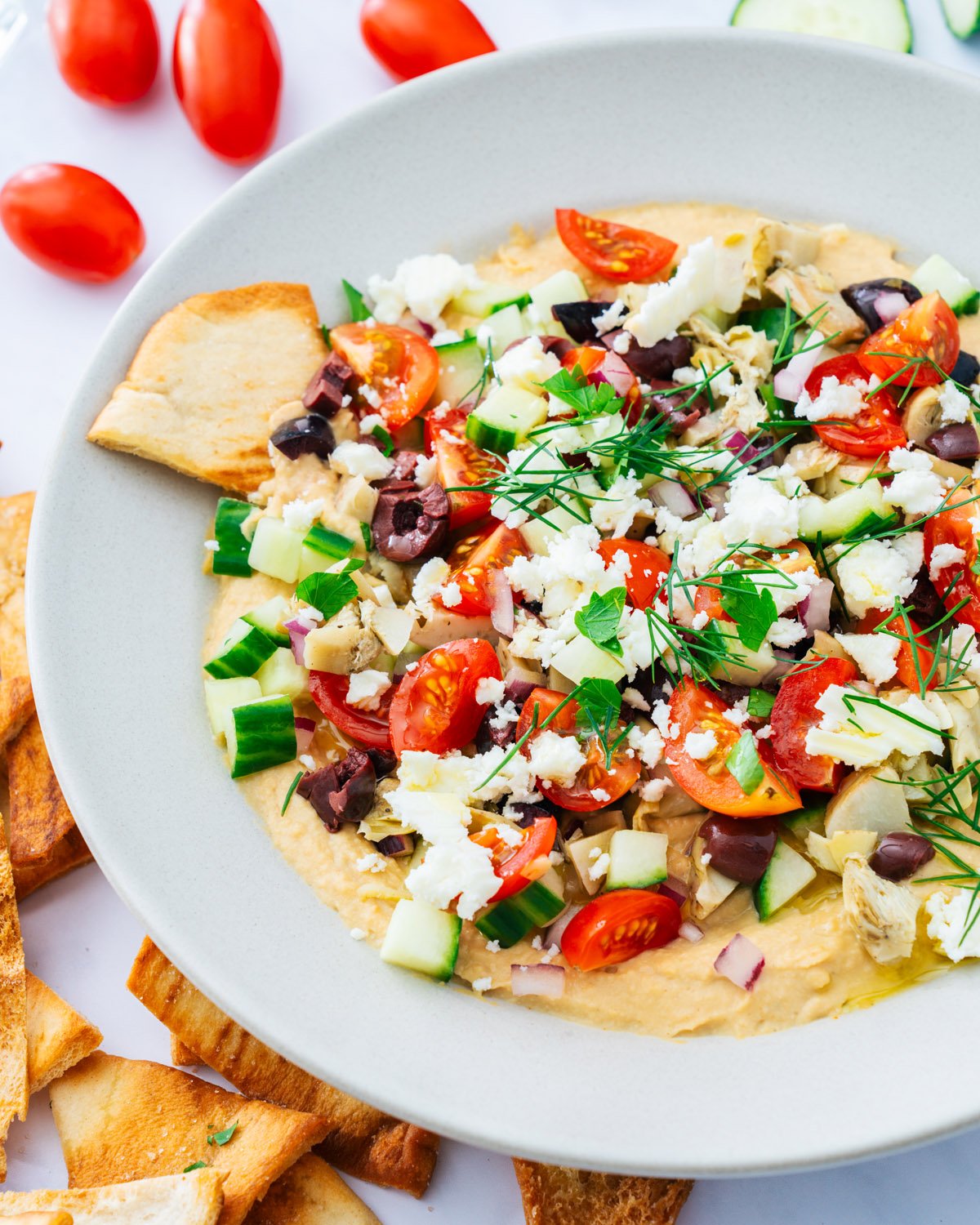 Mediterranean Diet snacks: hummus dip in bowl with veggie toppings and pita chips.